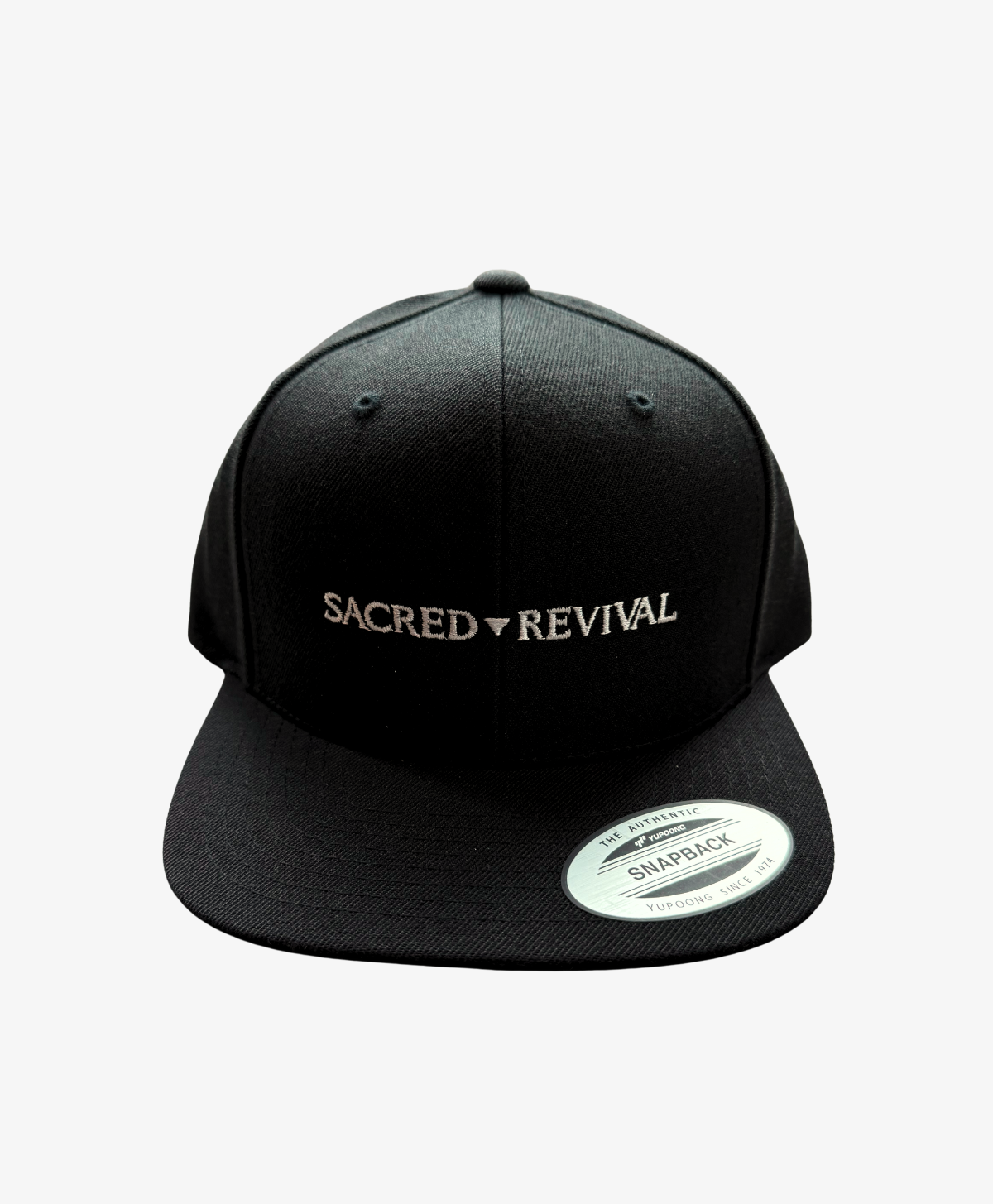 Black Sacred Revival snapback cap, front view, with the wordmark embroidered in white