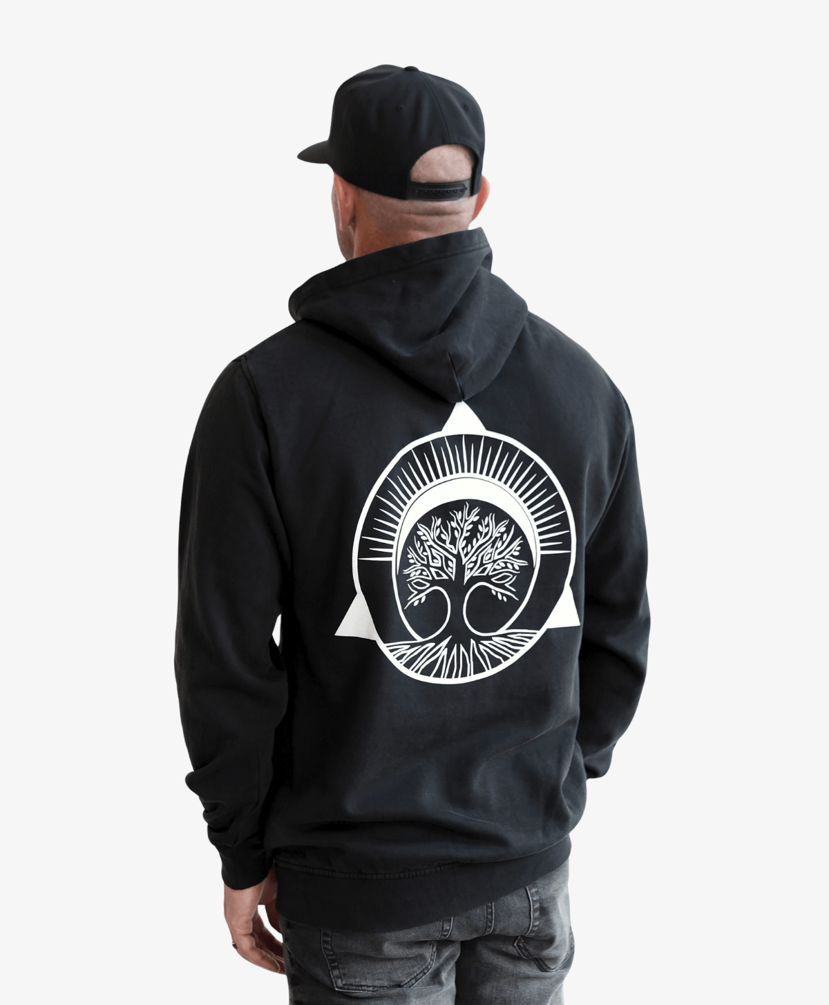 Man in a cap seen from behind wearing the black Tree of Life hoodie