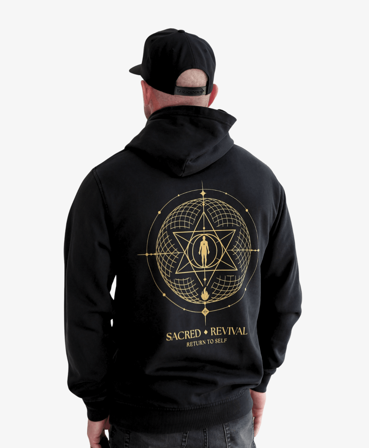 Man in a cap seen from behind wearing the black Return to Self hoodie