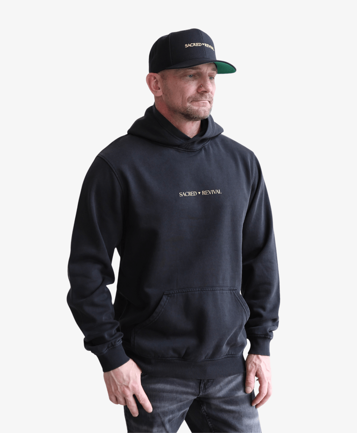 Man in a cap wearing the black Tree of Life vintage hoodie, front view