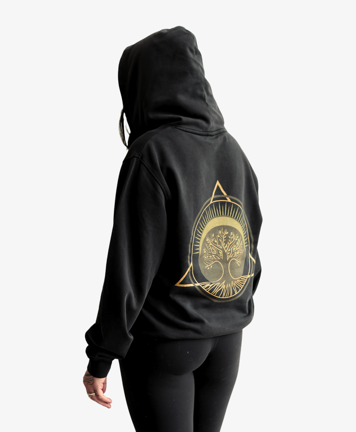 Woman seen from behind wearing the black Tree of Life vintage hoodie with the gold symbol