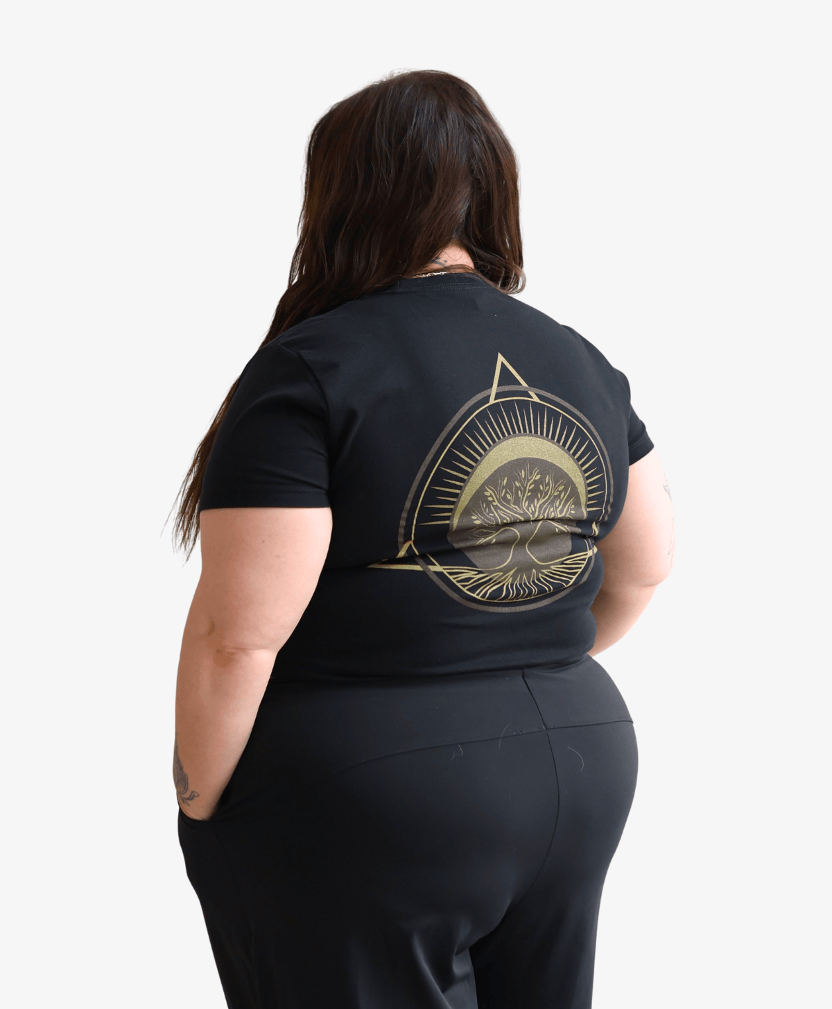 Woman seen from behind wearing the black Tree of Life tee with the gold symbol